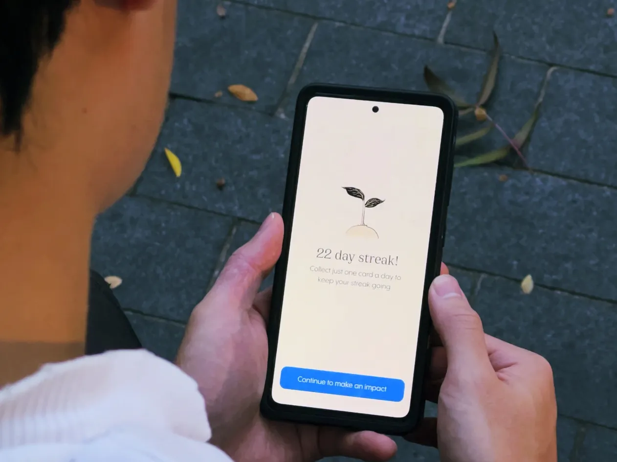 Someone holding a phone outdoors showing their Climasaur streak screen.