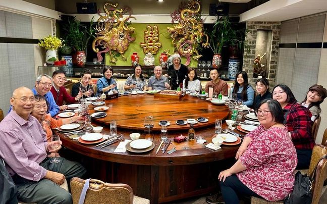 Large family gathering around a Chinese round dining table. Everyone is happy and the atmosphere is warm and inviting.