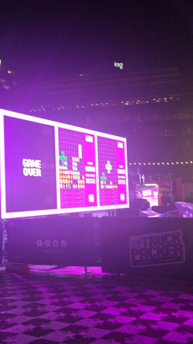 A tetris-like game projected onto the side of a truck, with three people playing at once.